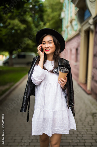 Asian womanwith hat and sunglasses cell phone call talking city street