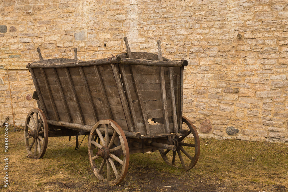 An old horse-drawn carriage stands near a stone wall.