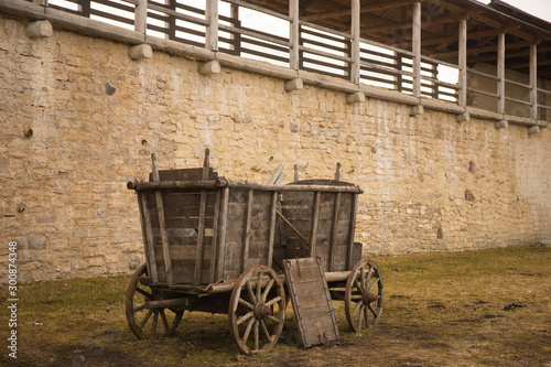 An old horse-drawn carriage stands near a stone wall.