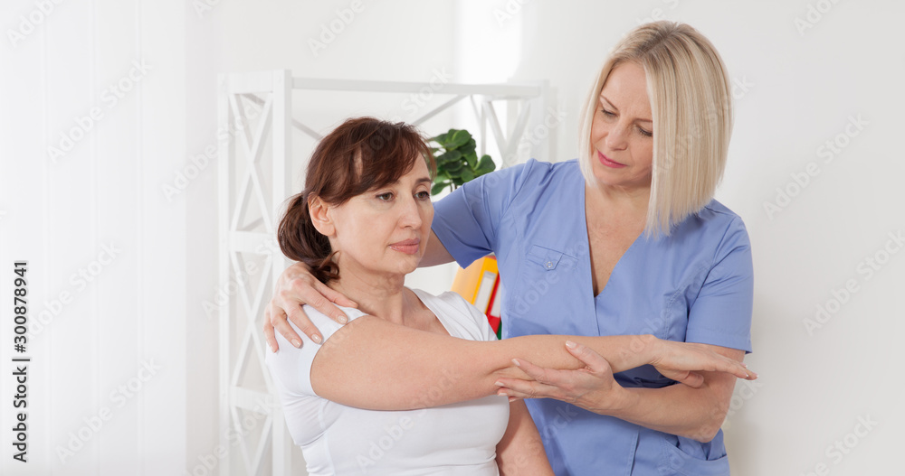 Obraz premium Physiotherapist working with middle aged patient in clinic