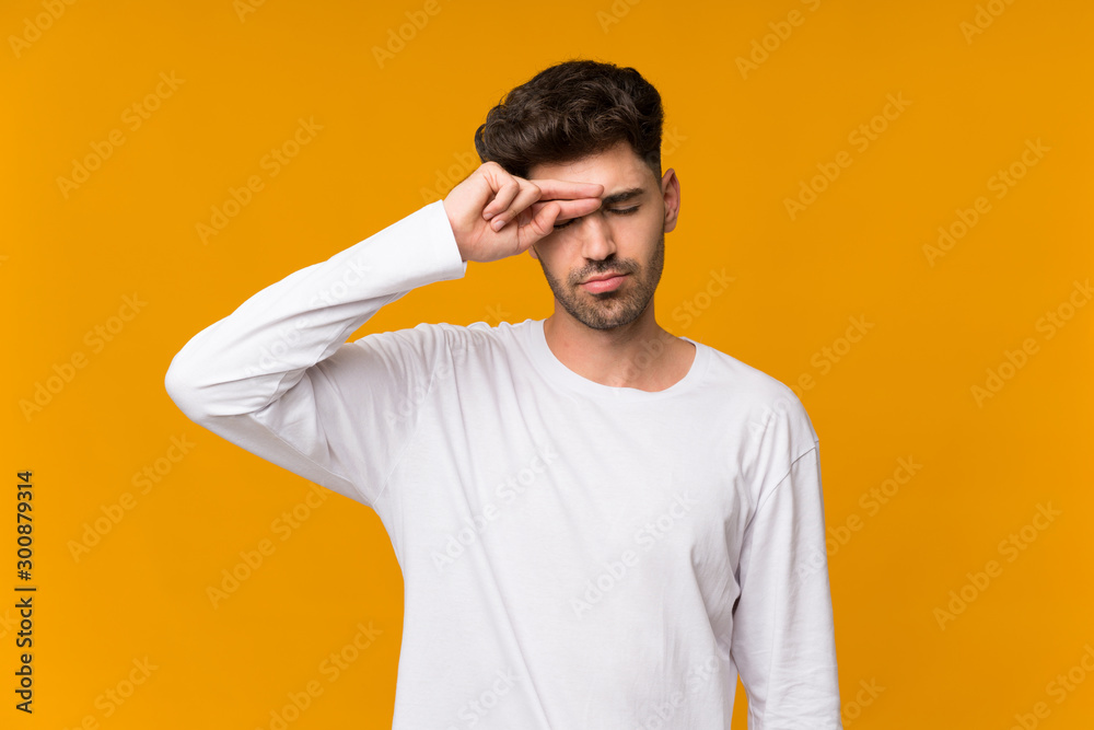 Young man over isolated orange background with tired and sick expression Young man over isolated orange background with tired and sick expression