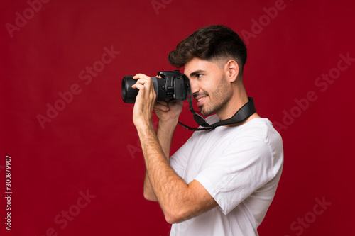 Young man over isolated background with a professional camera