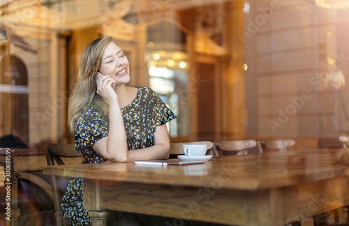 Beautiful young woman using smartphone at cafe