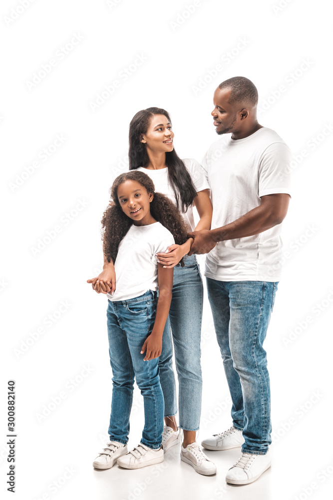happy african american husband and wife looking at each other while standing near adorable daughter on white background happy african american husband and wife looking at each other while standing near adorable daughter on white background