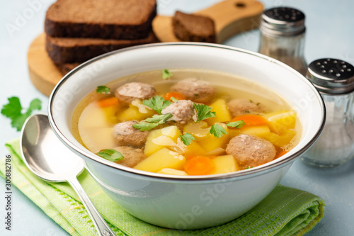 Soup with meatballs and vegetables in bowl on concrete background. Selective focus.