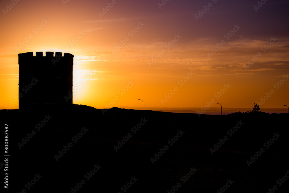 Silhouette of tower eclipsing the sun at sunset