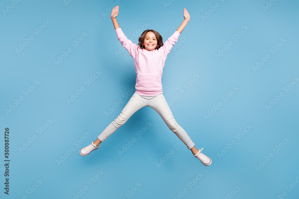 Full length body size photo of cheerful positive toothy beaming girl stretching her arms and legs pink shaping star jumping up isolated pastel blue color background