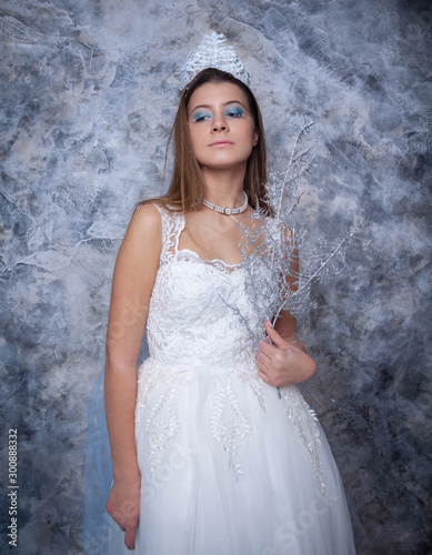 the snow Queen. Studio shooting a girl in a long white dress and a crown on a blue background