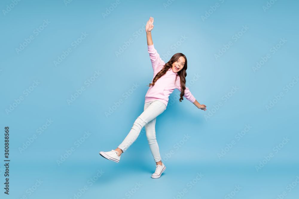 Full length body size turned photo of positive pink cheerful ecstatic overjoyed preteen balancing to prevent falling curly wavy isolated blue pastel color background