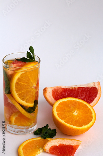 Fototapeta Naklejka Na Ścianę i Meble -  glass of orange cocktail and orange with green mint on white background. Detox citrus cocktail. healthy lifestyle.