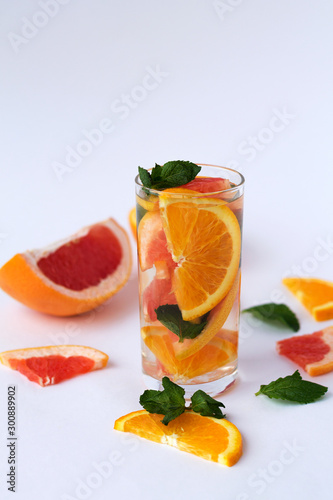 Detox citrus cocktail. healthy lifestyle. Fresh citrus fruit on white background. refreshing cocktail with slices of fresh orange and grapefruit with green mint leaves on white background. © Yashina