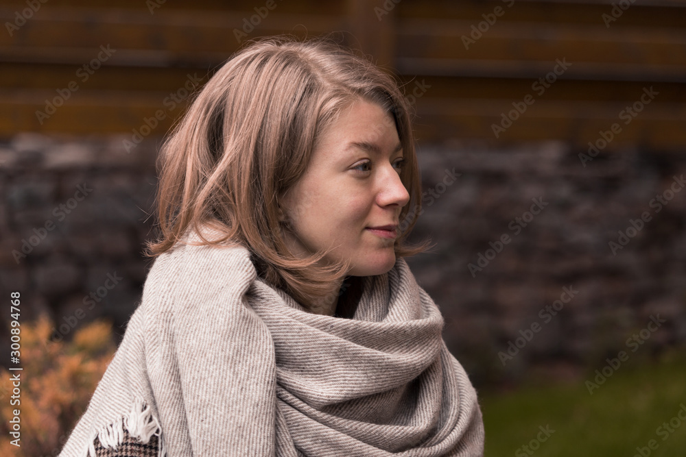 Blonde girl in a scarf and a checkered coat in autumn weather.