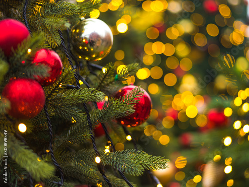 Winter Christmas holiday background - toys on a Christmas tree branch and blurry lights in the background in the background