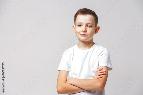 Portrait of young displeased boy with cross arms on white background