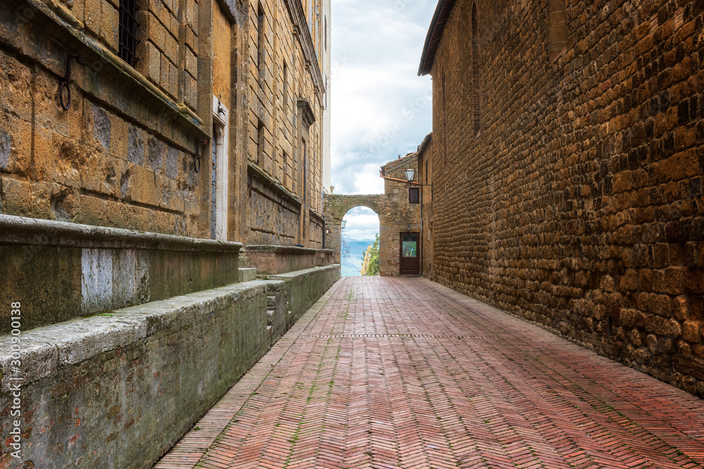 Gate to the valley / Amazing view with a narrow medieval street with arch gate in old town of Pienza in Tuscany, Italy