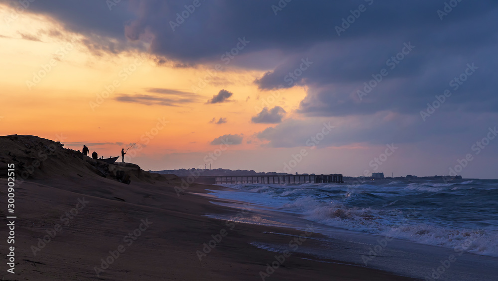 Fishermen catch fish on the seashore at sunset