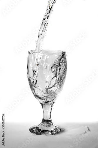 Pour water onto a glass of water with splash isolated on white background