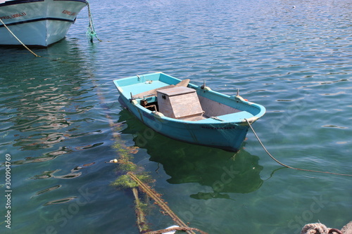 Blue little wooden boat with rope near the dock on the sea