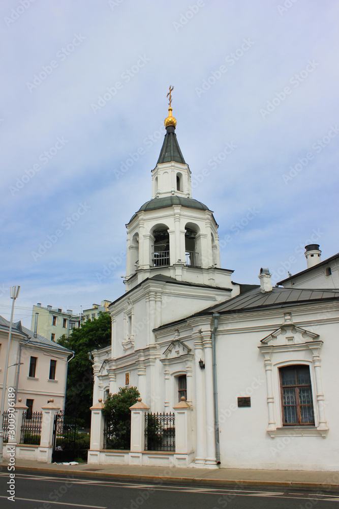 Church with bell tower located on small old town street. White monastery building outdoors on narrow city street 