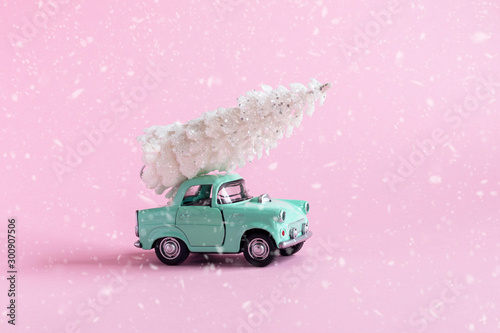 toy car with Christmas tree on it on pink background with snow texture , Christmas pr