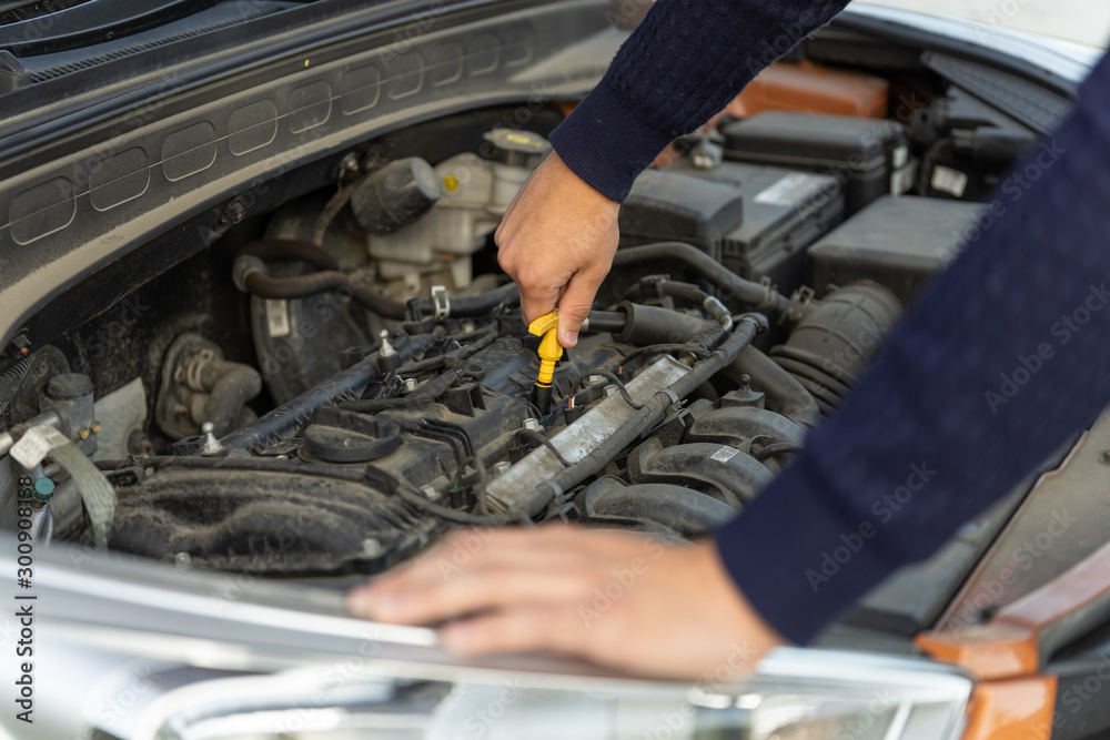 Male mechanic checking level of oil in car engine Male mechanic checking level of oil in car engine