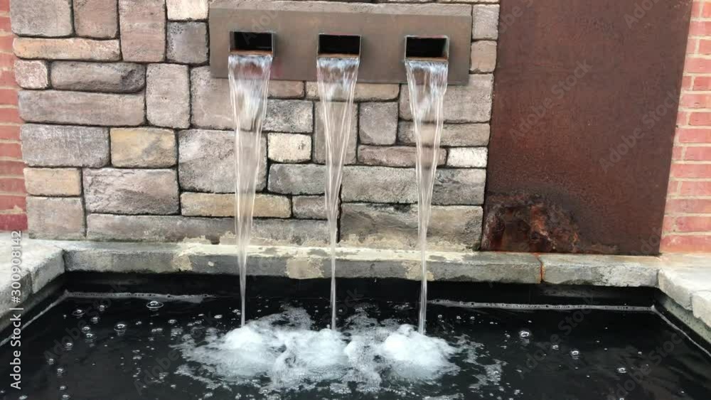 Close up of water flowing from wall fountain with vintage bricks as background