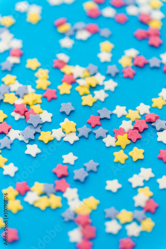party, sweets and decoration concept - star shaped sugar sprinkles on blue background