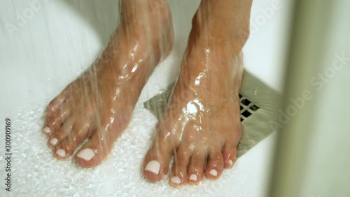 Young beautiful woman taking a shower in a bathroom. Close-up shot of female feet. Slow motion. HD