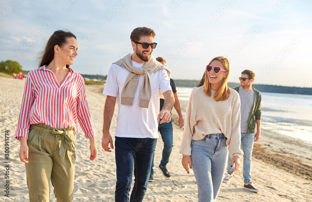 friendship, leisure and people concept - group of happy friends walking along beach in summer friendship, leisure and people concept - group of happy friends walking along beach in summer