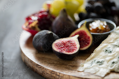 figs with cheese, grapes and honey on wooden board