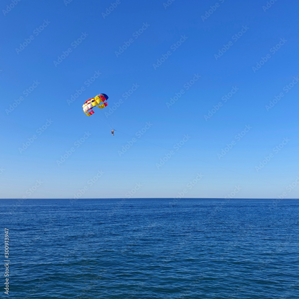 A man with a parachute flies over the sea. A man with a parachute flies over the sea.