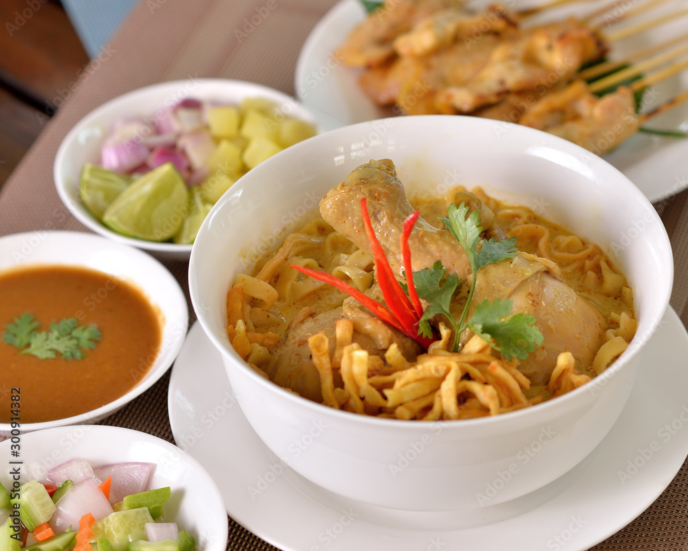 Khao Soi Chicken, northern Thai noodle dish with chicken and coconut curry soup, shown with crispy noodles and other vegetables Khao Soi Chicken, northern Thai noodle dish with chicken and coconut curry soup, shown with crispy noodles and other vegetables