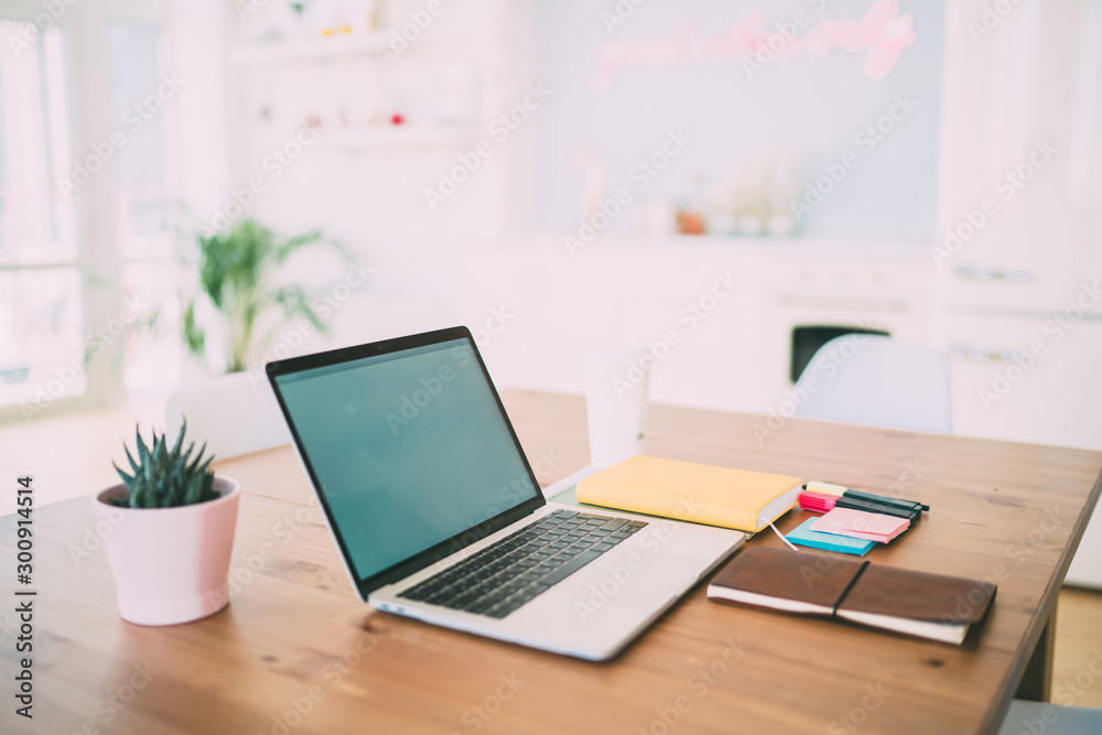 Opened laptop with white screen and notebooks on wooden table Opened laptop with white screen and notebooks on wooden table