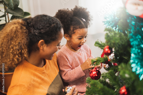 Black african mother and her cute daughter decorating christmas tree for christmas and happy new concept