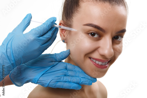 Facial Beauty Injections. Portrait Beautiful Young Woman Receiving Hyaluronic Acid Injection. Closeup Of Hands In Gloves Holding Syringe Near Attractive smiling Female Face.