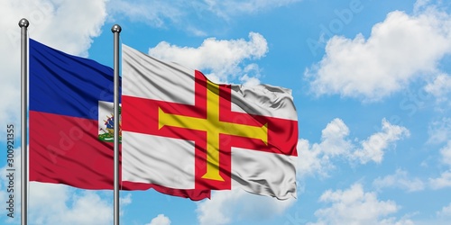 Φωτογραφία Haiti and Guernsey flag waving in the wind against white cloudy blue sky together