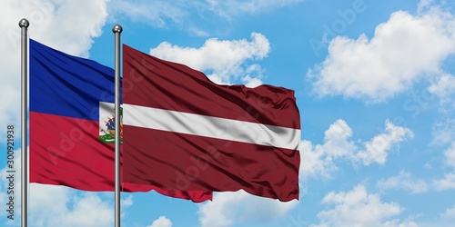 Fotografie Haiti and Latvia flag waving in the wind against white cloudy blue sky together