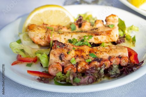 Fried octopus on plate with slice of lemon in taverna in Greece