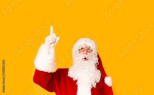 Santa Claus looking surprised and showing with finger on copy space