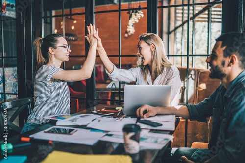 Happy women giving high five coworking in cafe