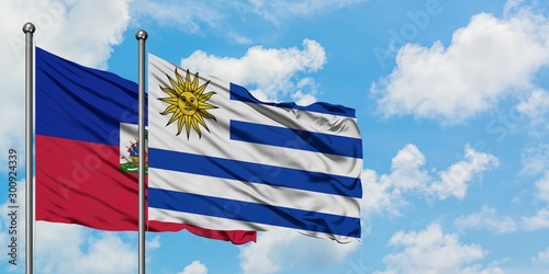 Obraz na płótnie Haiti and Uruguay flag waving in the wind against white cloudy blue sky together