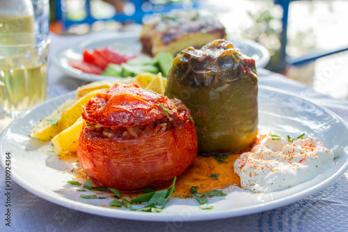 Greek traditional gemista, stuffed tomatoes and peppers on a white plate served in taverna with retsina, Greece
