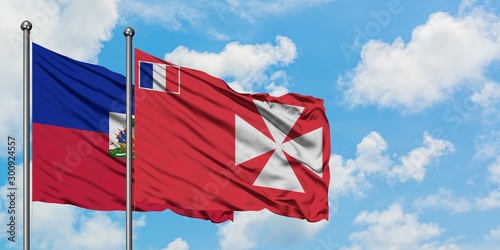 Fotografie Haiti and Wallis And Futuna flag waving in the wind against white cloudy blue sky together