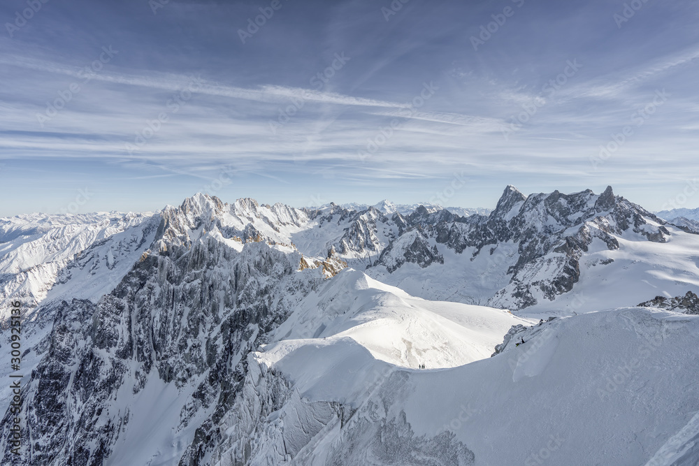 Skier hiker slowy walk down on a massive snow mountain slope on top of alps mont blanc