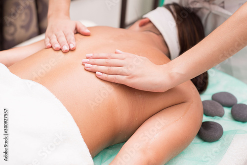 A young girl enjoys spa treatments. Hands of a massage therapist  beautician make massage.