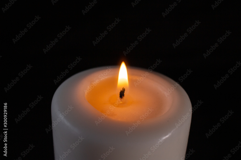 burning white candle large on a black background burning white candle large on a black background