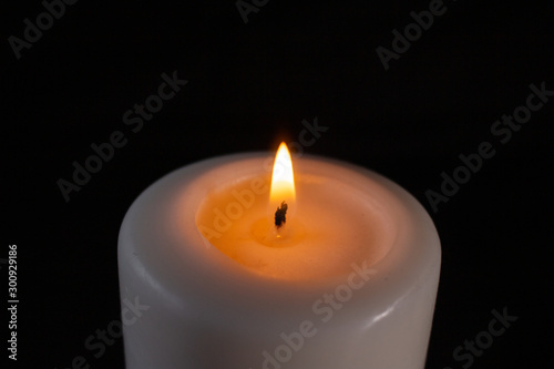 burning white candle large on a black background