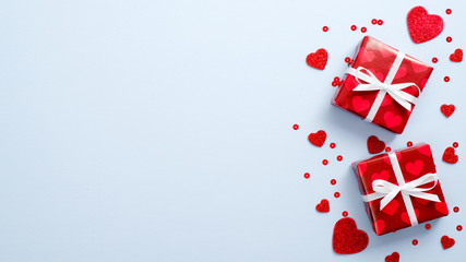 Valentine's Day, love concept. Greeting card mockup with red gifts and valentine hearts on blue background. Flat lay, top view, copy space