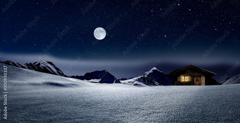 Gemütliche Holzhütte mit Beleuchtetem Fenster im verschneiten Hochgebirge  bei Nacht im Winter - obrazy, fototapety, plakaty 