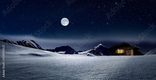 Gemütliche Holzhütte mit Beleuchtetem Fenster im verschneiten Hochgebirge  bei Nacht im Winter © by-studio